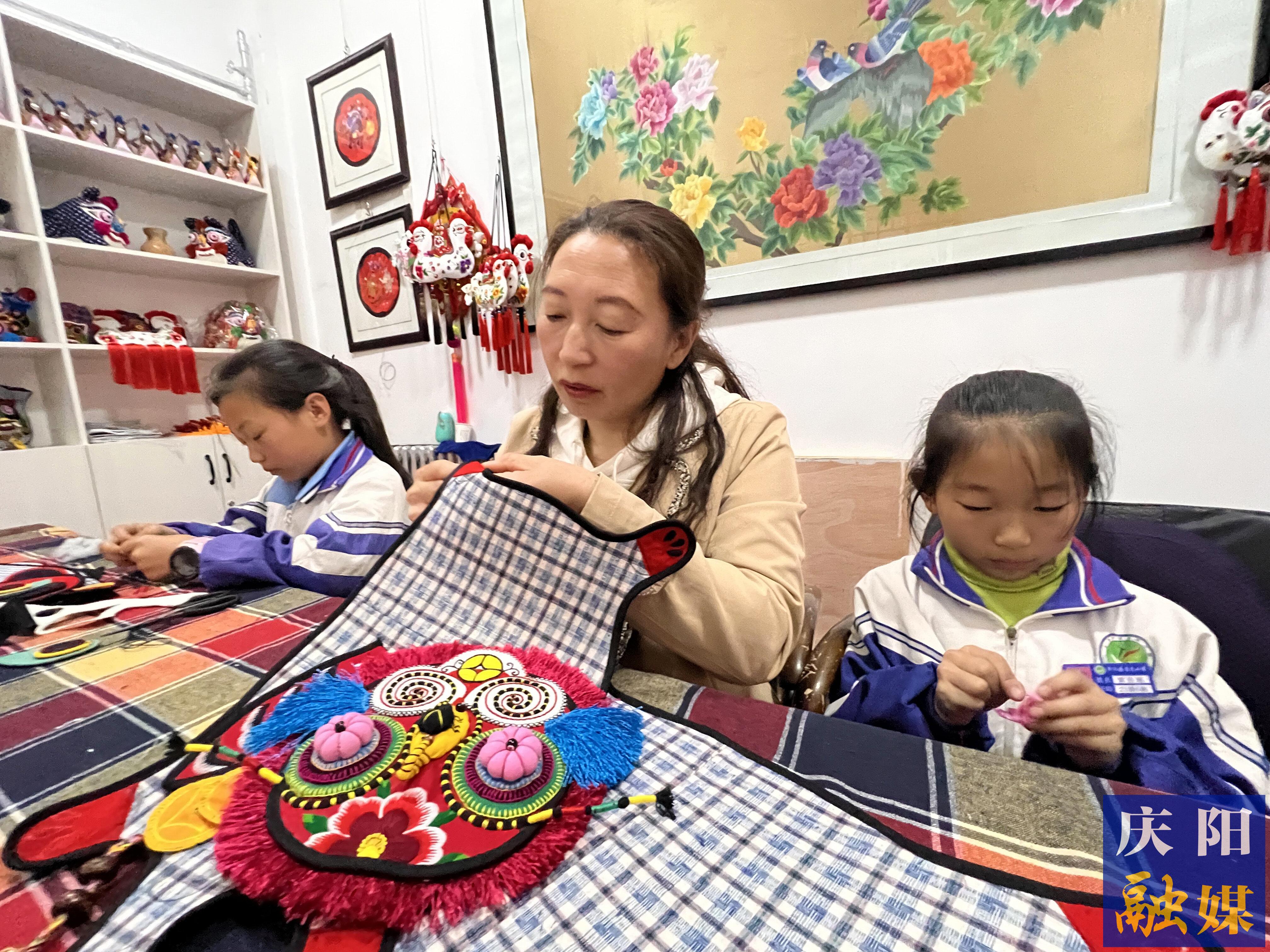 李富梅帶著自己的孩子完成刺繡作品。